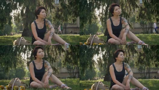 时髦的年轻亚洲女性潮人与纹身坐在草地上附近的大学，深思高清在线视频素材下载