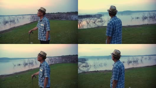 场景慢镜头中，一名年长的亚洲男子拄着拐杖站在湖边欣赏大自然，他在假期里开心玩乐，放松的时刻。高级自然户外日常生活概念高清在线视频素材下载