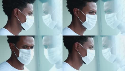 非洲男子戴着冠状病毒口罩在家看窗外高清在线视频素材下载