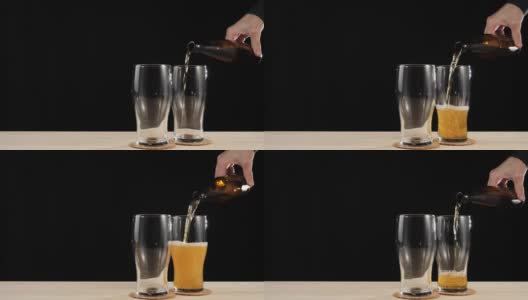 新鲜的啤酒。在黑色背景的木桌上，手从一个棕色的瓶子里将美味的精酿啤酒倒进啤酒杯。冰凉的新鲜啤酒，带有水滴，泡沫和泡沫。4 k高清在线视频素材下载