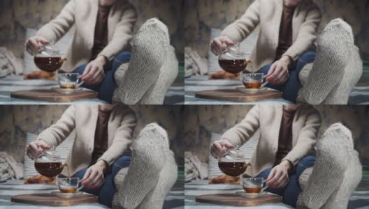成熟的女人正坐在沙发上喝茶。注重脚上穿的羊毛手工袜子高清在线视频素材下载