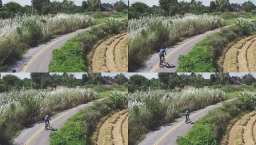 无人机拍摄到一名男子在当地道路上骑自行车高清在线视频素材下载