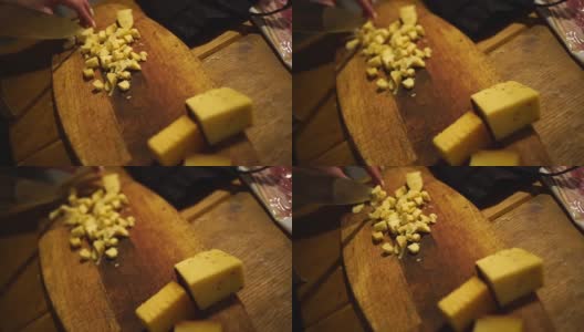低光。女人的手在砧板上把奶酪切成小块高清在线视频素材下载