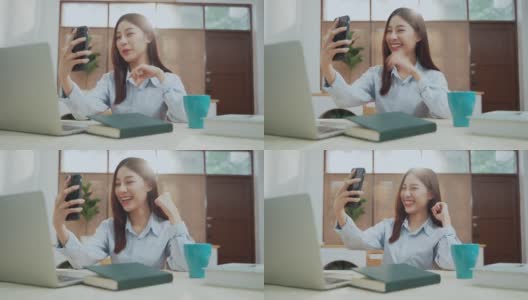 年轻美丽的亚洲女性与智能手机聊天使用笔记本电脑在家庭办公室工作高清在线视频素材下载