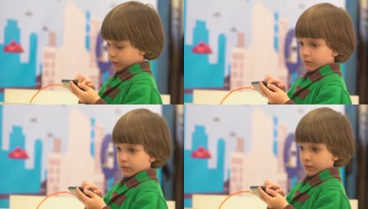 可爱的小男孩在用智能手机。在第四届俄罗斯科学节上为儿童展示的机器人。该活动旨在普及科学和展示技术进步。可爱的小男孩在玩电子玩具机。情感、兴趣高清在线视频素材下载