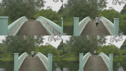 一个穿着运动服的女人在早晨慢跑过天然池塘上的旧混凝土桥的后向镜头的公园。健康的生活方式。无污染的环境。高清在线视频素材下载