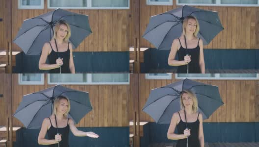 迷人的金发女郎在下雨时撑着伞。一个在夏日淋浴的女人高清在线视频素材下载