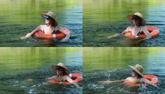 一名身穿泳衣、头戴草帽的女子带着一个充气圈漂浮在湖、河的池塘里。女孩休息在游泳池游泳圈与蓝色的水高清在线视频素材下载