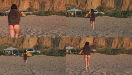 日落时分，一个女人在海滩边用毛巾擦干身体高清在线视频素材下载
