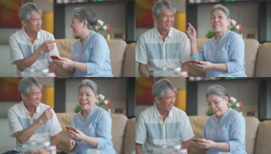 快乐的亚洲华人祖父母使用电话，在客厅愉快地交谈高清在线视频素材下载