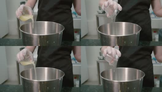 在厨房里，一名妇女从玻璃杯中将黄色液体倒入炖锅高清在线视频素材下载