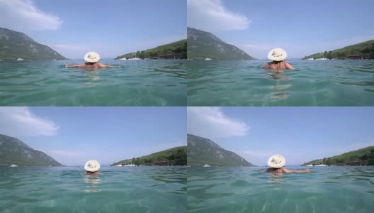 中年妇女戴着帽子，跳进海里。Marmaris土耳其高清在线视频素材下载