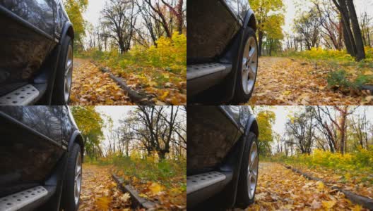 从前轮近距离观看强大的汽车行驶在公园道路上的黄叶。一辆黑色汽车在阳光明媚的日子穿过小巷。秋季公园里的越野车。慢动作高清在线视频素材下载
