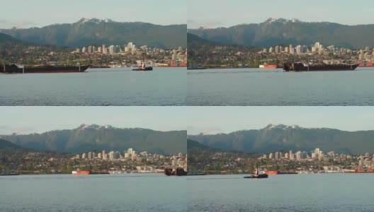 一艘拖船拖着一艘大型工业船在温哥华港前的工业区和山区。高清在线视频素材下载