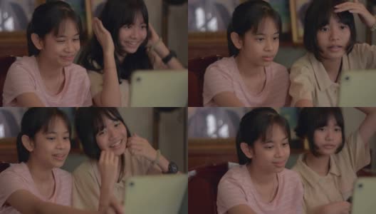 两个亚洲可爱女孩喜欢在家里用电子平板电脑和朋友视频聊天。现代年轻人的生活方式。通过数字设备直播的社交网络交流。高清在线视频素材下载
