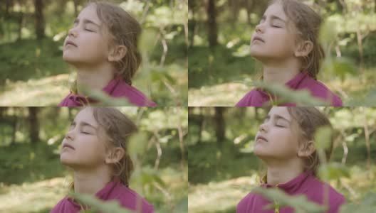 肖像小女孩在森林中呼吸新鲜空气，深呼吸，减轻压力。梦幻宁静放松微笑的小女孩呼吸着新鲜的空气自然，宁静的高加索孩子独自在户外。高清在线视频素材下载