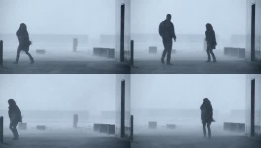 在冰岛雷克雅未克的暴风雪中，一名男子和一名女子站在建筑外高清在线视频素材下载