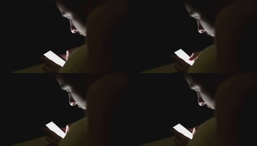 年轻人晚上在床上盖着毯子使用智能手机高清在线视频素材下载