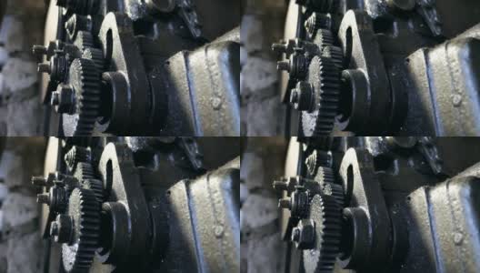 关闭转动齿轮系统。低角度查看脏旋转齿轮的金属工作台在车库工作。模糊的背景。慢动作高清在线视频素材下载