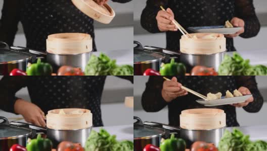 一个女人的选择性焦点，打开竹制蒸笼的盖子，把饺子放进去。传统的中国食物和烹饪理念。高清在线视频素材下载