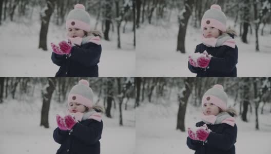 小女孩试着把手套上的雪吹掉高清在线视频素材下载