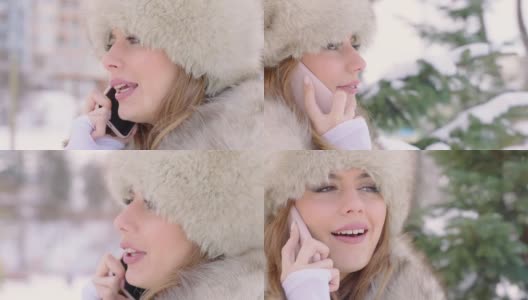 美丽的女人戴着皮草帽在冬天的公园里使用智能手机在下雪的天气下高清在线视频素材下载