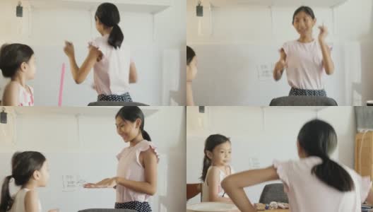 快乐的亚洲女孩用白板教姐姐数学，女孩在家里做运动，COVID-19期间在家自学。高清在线视频素材下载