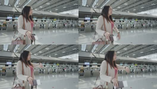 一名亚洲女性旅客在机场，拿着行李看她旅行的航班时间，登机前在屏幕上看新的旅行时间，旅行假期，侧视高清在线视频素材下载