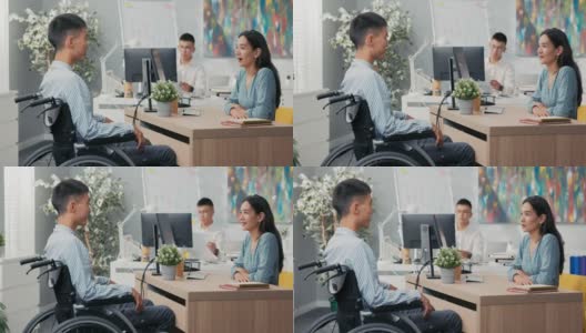 一个坐着轮椅的残疾人面试，一个亚裔韩国美女向穿着衬衫的男孩提问，她听着他们坐在公司办公室桌子两边的答案高清在线视频素材下载