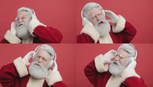 时髦开朗的圣诞老人戴着耳机听音乐，在红色的背景下唱歌跳舞。圣诞精神，圣诞晚会结束高清在线视频素材下载