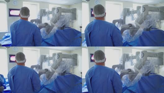 现代化手术室里的高科技设备。外科医生在医疗机器人附近的后视图。医生用机器人系统做手术，看着屏幕。高清在线视频素材下载