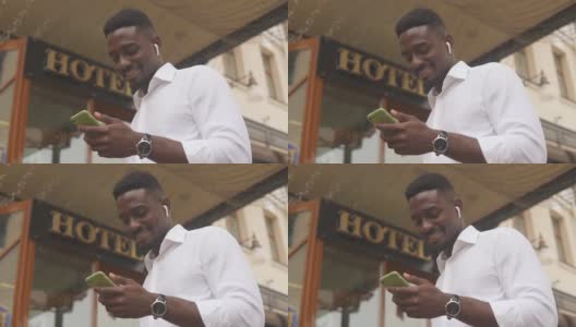 一名非洲裔美国人站在酒店外使用智能手机高清在线视频素材下载