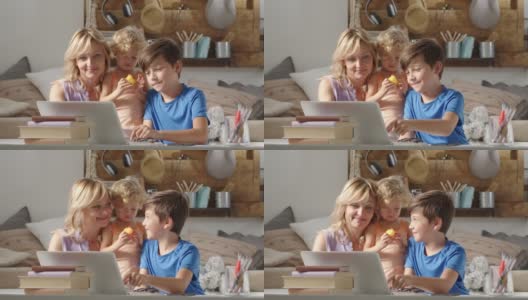 快乐的家庭在家里，母亲和儿子和女儿玩电脑，父母和孩子在笔记本电脑上浏览互联网，男孩学生在显示器上显示一些东西高清在线视频素材下载