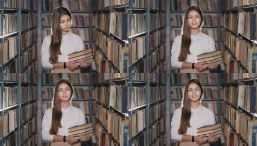 一个十几岁女孩的肖像和书在图书馆里高清在线视频素材下载