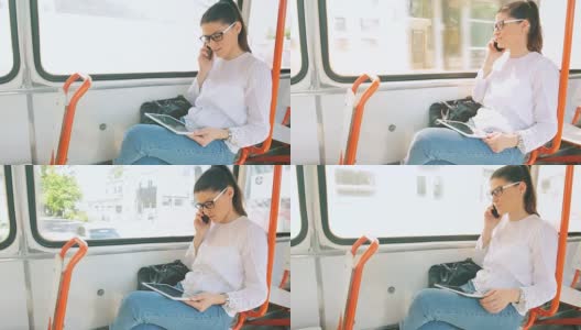 一名年轻女子在有轨电车里一边用平板电脑一边用手机说话。高清在线视频素材下载