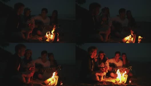 年轻人晚上在海滩上用篝火野餐。欢快的朋友们唱着歌，弹着吉他。Slowmotion拍摄高清在线视频素材下载