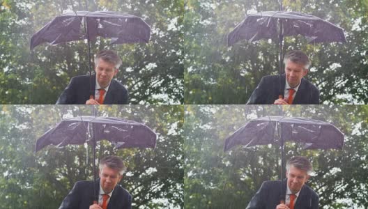 一个商人在雨中躲在一把破伞下高清在线视频素材下载