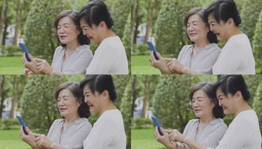 两位台湾资深女性一边看智能手机一边笑高清在线视频素材下载