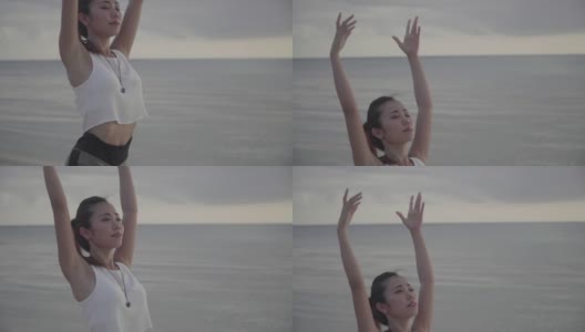 一名千禧年妇女在户外沙滩上练习瑜伽的中镜头高清在线视频素材下载