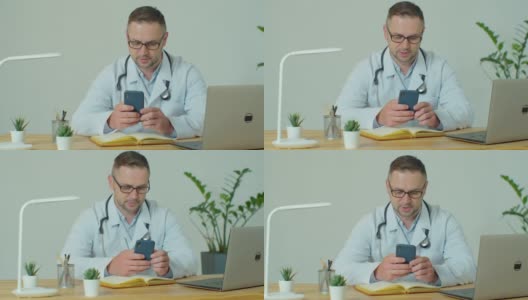 穿着白大褂的男医生使用带有触摸屏的现代智能手机。医生使用手机向患者发送短信，告知医疗检查结果。高清在线视频素材下载