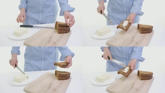 女性的双手在厨房的面包上涂抹黄油的特写。白色backgound高清在线视频素材下载