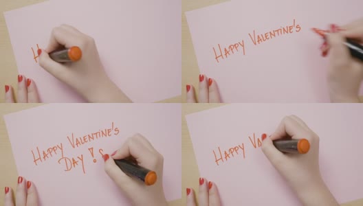 女人用红色记号笔在粉红色的纸上用大写字母写下“情人节快乐”高清在线视频素材下载