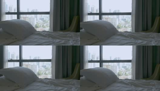抬起一张空床，上面有两个枕头，可以看到大城市的景色高清在线视频素材下载