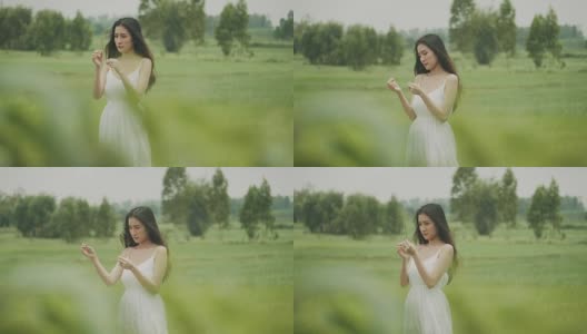 泰国美丽的女人背着草，而微笑和快乐与绿色的农场区域高清在线视频素材下载