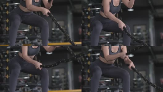 运动运动员在交叉健身馆用格斗绳锻炼，女性在运动服训练健康健美，运动员肌肉生活理念，慢镜头。高清在线视频素材下载