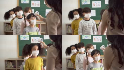 一组学生在教学楼内进行温度检查和扫描。小学生们都戴着口罩，排队进入教室。高清在线视频素材下载