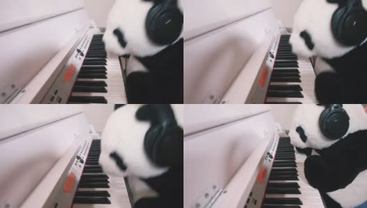 毛绒玩具熊猫弹奏电子钢琴琴键，耳机落下。音乐播放的乐趣。高清在线视频素材下载