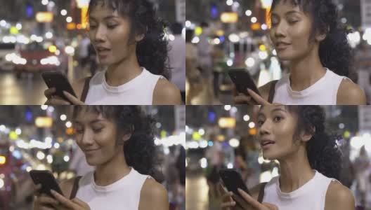 一个美女在夜市用智能手机。高清在线视频素材下载