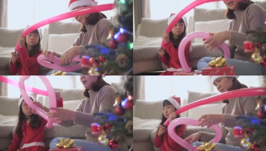 小女孩和妈妈在圣诞节期间用装饰品装饰圣诞树高清在线视频素材下载