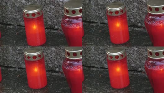 下雨天在墓地的墓碑上排着火红的纪念蜡烛。墓碑上的坟墓，雨滴落得紧紧的。亡灵日高清在线视频素材下载